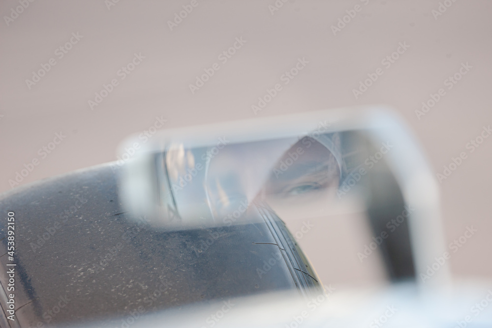 Close up of car side-view mirror with reflection of racer Close up of car side-view mirror with reflection of racer