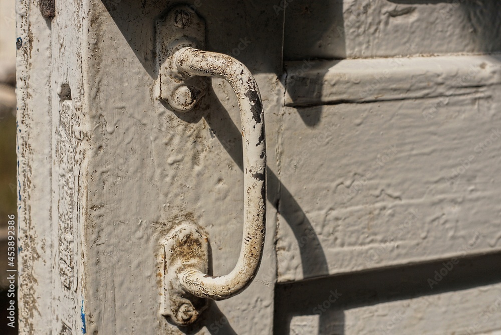 one old dirty gray iron doorknob on white wooden door planks