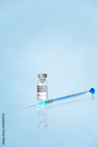 Vial, frasco y jeringa con medicamento vacuna Covid-19 fondo azul claro