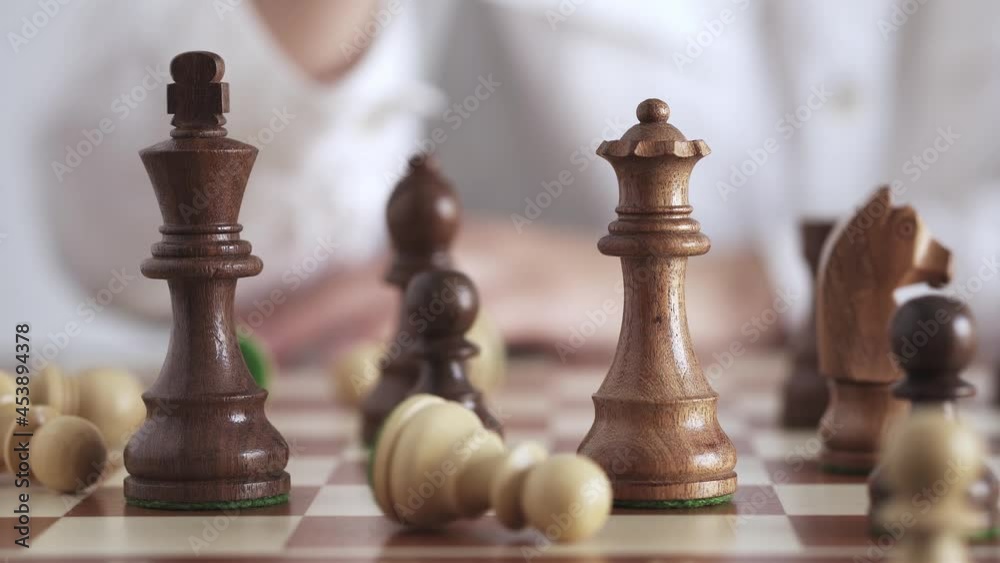 Wood chessboard during game. Queen's move. Movement of queen's piece on chessboard. Woman plays wooden chess. Person makes move in chess game. Concept of successful business woman, strategic thinking. Wood chessboard during game. Queen's move. Movement of queen's piece on chessboard. Woman plays wooden chess. Person makes move in chess game. Concept of successful business woman, strategic thinking.