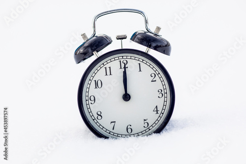 The clock in the snow shows the time at 12 o'clock. winter coming soon concept.