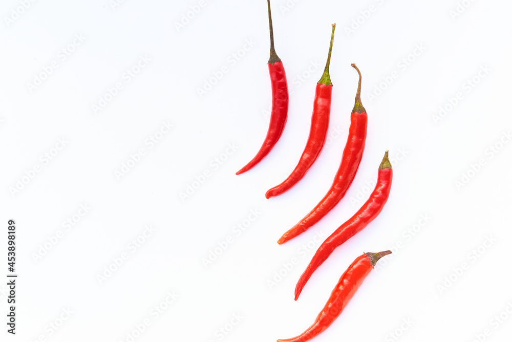 Red fresh chili peppers on white background in the centre, flat lay, copy space, top view. Red fresh chili peppers on white background in the centre, flat lay, copy space, top view.