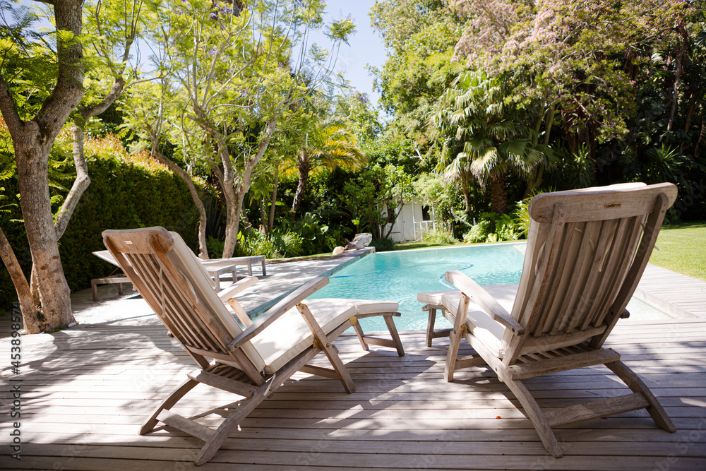 Lawn chairs and swimming pool in backyard