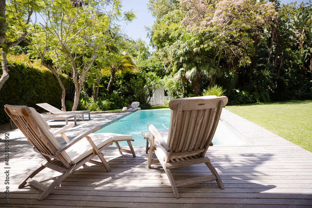Lawn chairs and swimming pool in backyard
