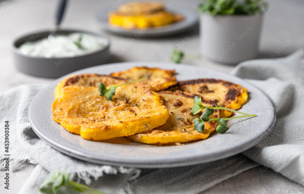 Fried patisson or yellow zucchini with sauce and micro greens, grey concrete background. Fried patisson or yellow zucchini with sauce and micro greens, grey concrete background.