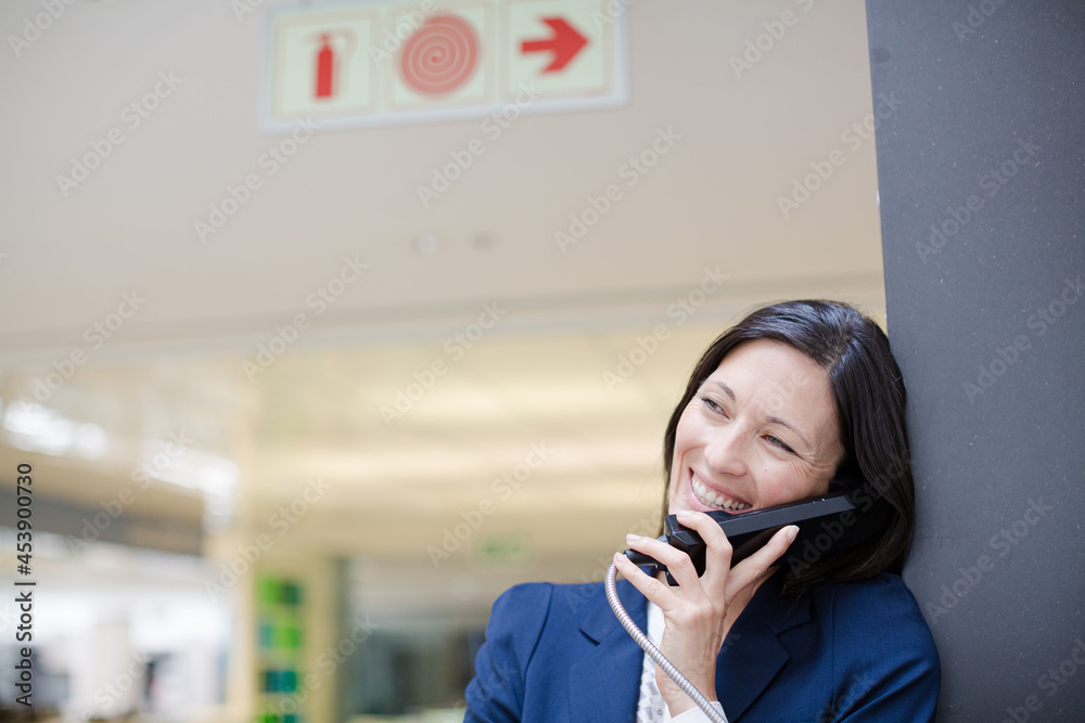 Businesswoman talking on pay phone outdoors Businesswoman talking on pay phone outdoors