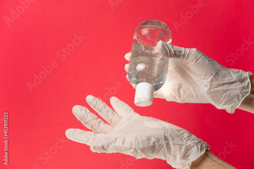 Enfermero/enfermera colocándose alcohol en gel con guantes de látex, fondo rojo photo