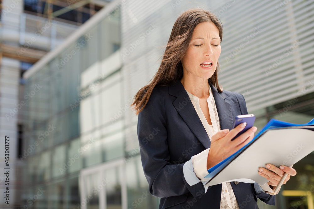 Businesswoman with folders talking on cell phone Businesswoman with folders talking on cell phone