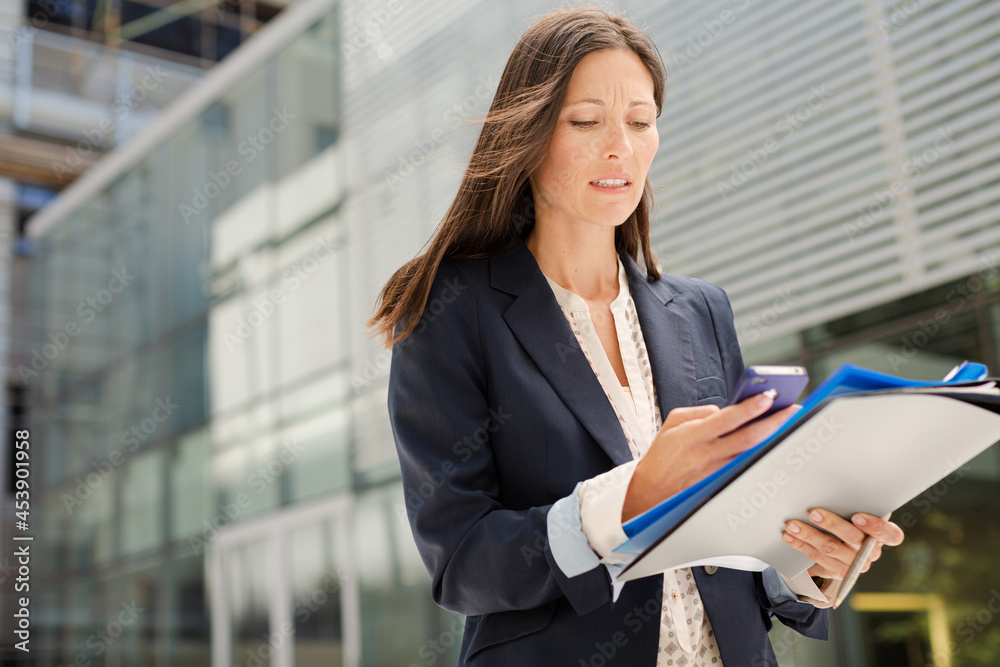Businesswoman with folders talking on cell phone Businesswoman with folders talking on cell phone