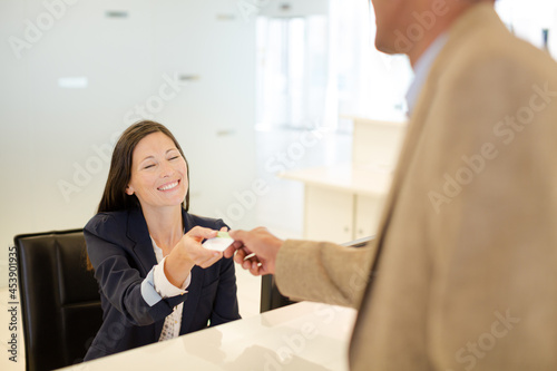 Businesswoman handing credit card to coworker
