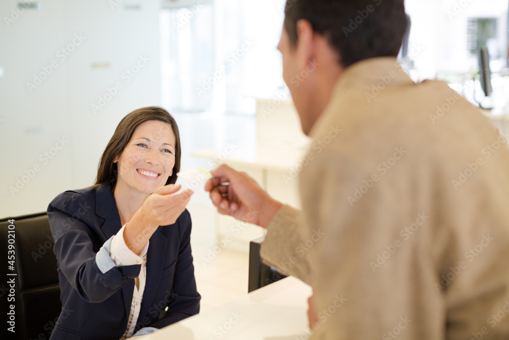 Businesswoman handing credit card to coworker Businesswoman handing credit card to coworker