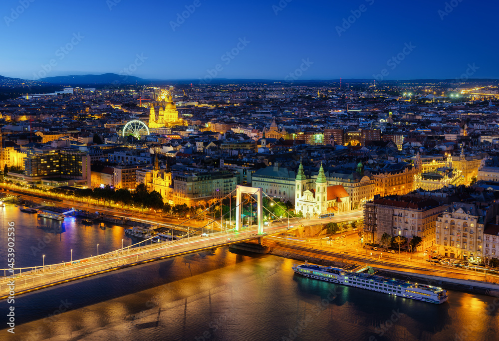 View of Budapest at night, Hungary. A cityscape in Europe. Ferris wheel and ancient architecture. Bridges and the Danube River. Landscape from above.