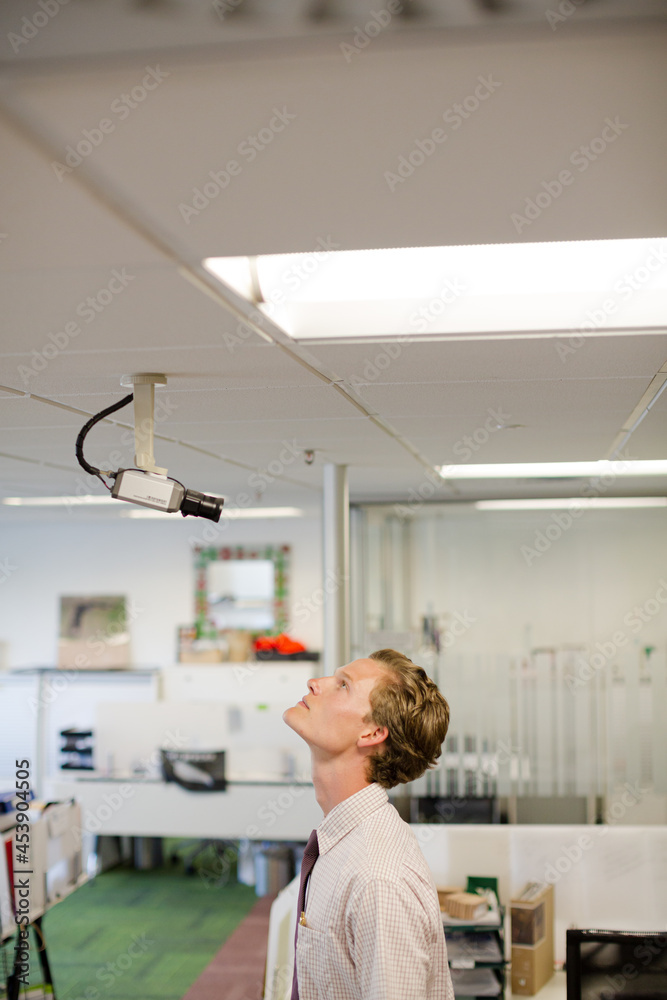 Businessman examining security camera in office Businessman examining security camera in office