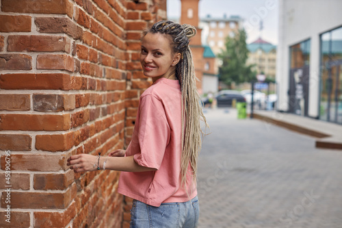 portrait of a cheerful young woman in a pink T-shirt against the background of a city street, Walks around the city. High quality photo