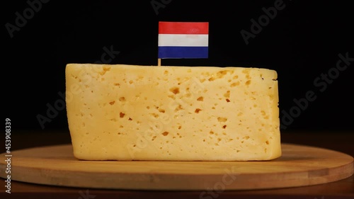 Man's hand put small in size toothpick with dutch flag on cheese.
