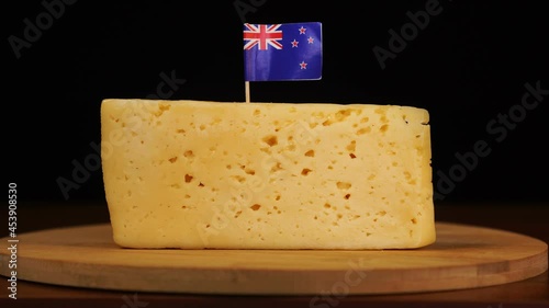 Man's hand put small in size toothpick with New Zealand flag on cheese.