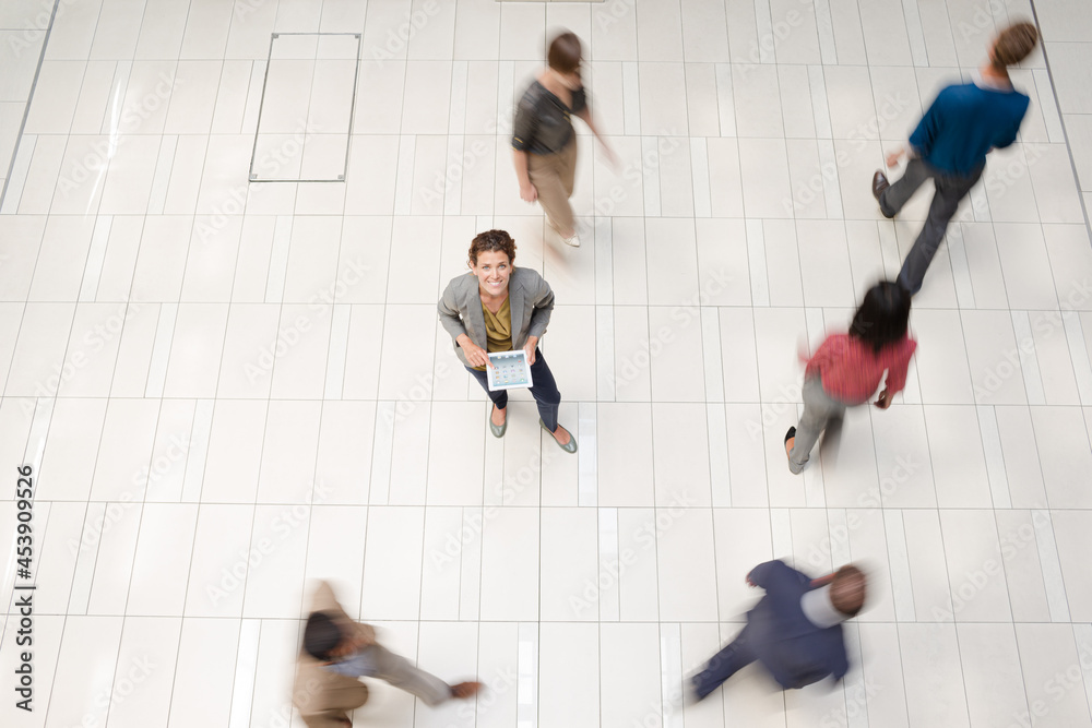 Obraz premium Businesswoman standing in busy office hallway