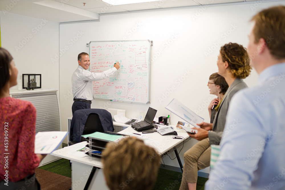 Fototapeta premium Businessman drawing on whiteboard in meeting