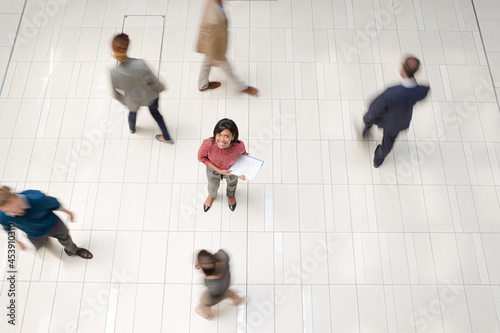 Businesswoman standing in busy office hallway © KOTO