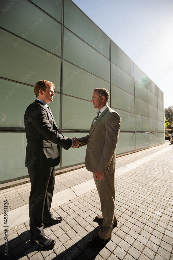 Businessmen shaking hands on city street Businessmen shaking hands on city street