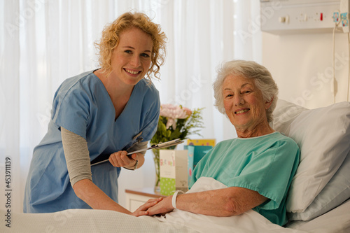 Portrait of smiling nurse and senior patient in hospital room