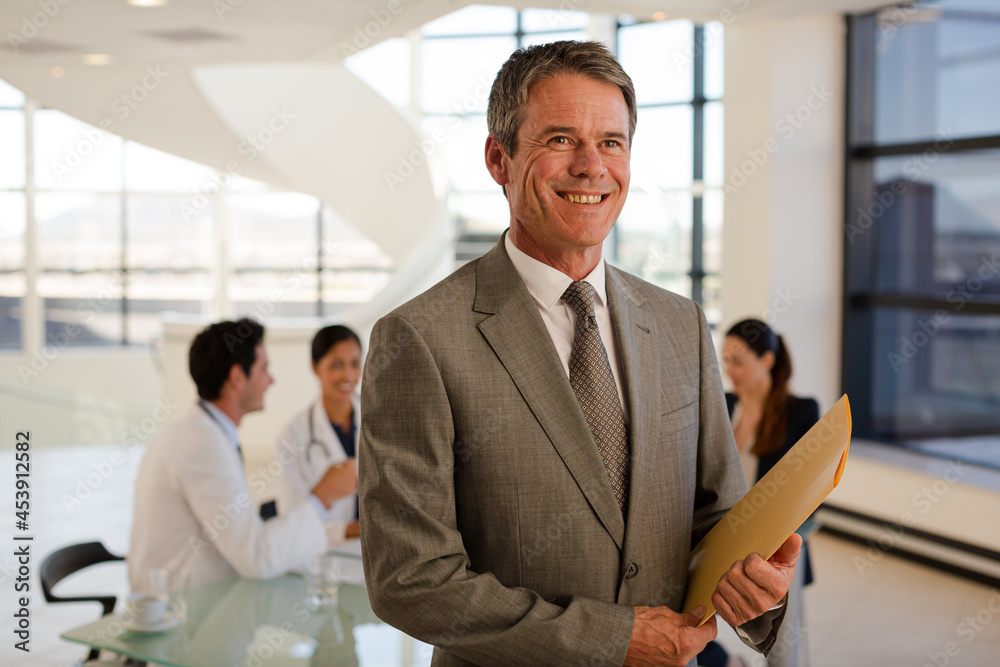 Portrait of smiling businessman in meeting with doctors Portrait of smiling businessman in meeting with doctors