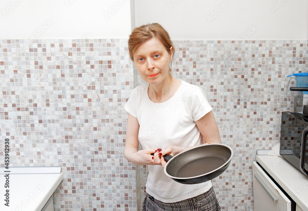 Young woman holding frying pan in kitchen Young woman holding frying pan in kitchen