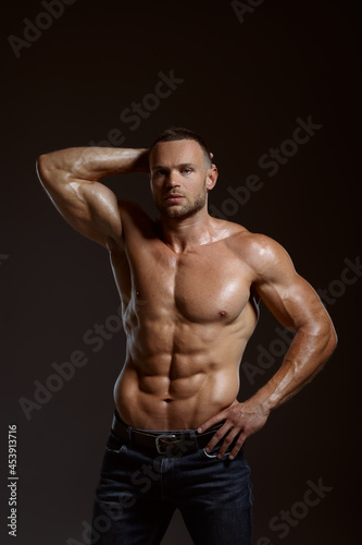 Male athlete with muscular body poses in studio