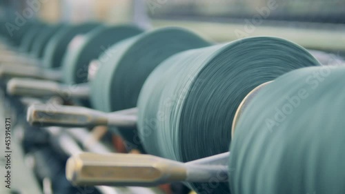 Thread spools are rotating in the textile machinery in a close up photo