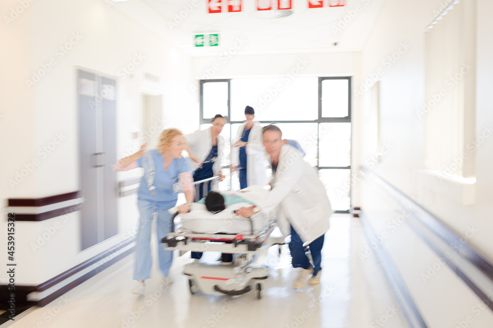 Obraz premium Doctors rushing patient on gurney in hospital corridor