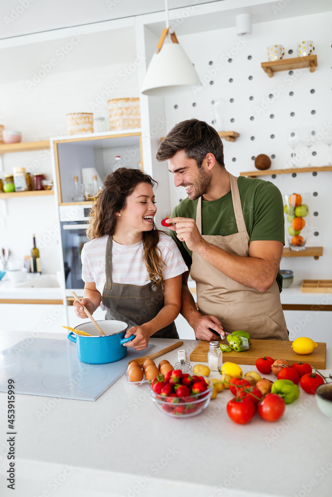 Happy young couple have fun in modern kitchen while preparing fresh food