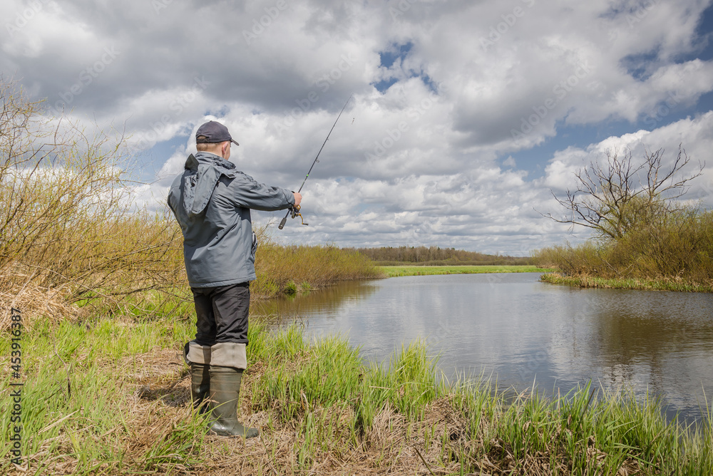 Fisherman throws spinning rod on the river bank. Fisherman throws spinning rod on the river bank.