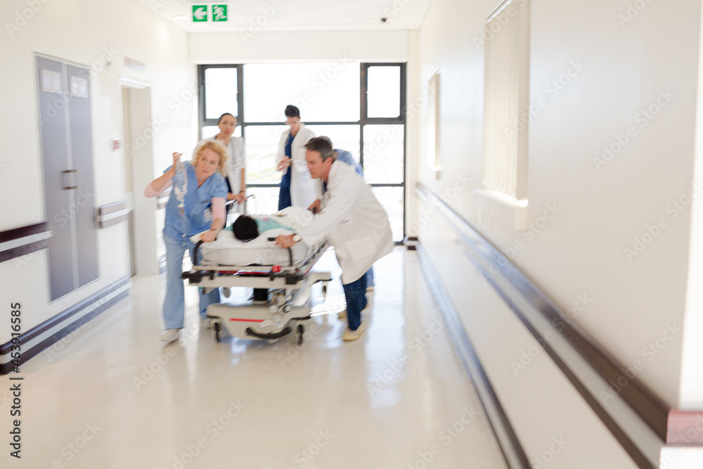 Doctors rushing patient on gurney in hospital corridor Doctors rushing patient on gurney in hospital corridor