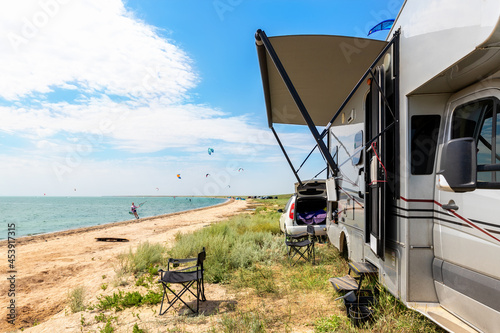 Print op canvas Panoramic view of many surf board kite riders on sand beach watersport spot on bright sunny day against rv camper van vehicle at sea ocean coast at surfing camp