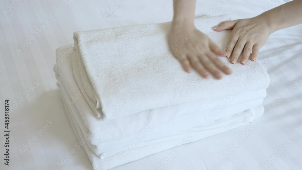 Closeup hands putting a stack of new clean bath towels on the bed. Hotel room service concept. 4K slow motion footage. Closeup hands putting a stack of new clean bath towels on the bed. Hotel room service concept. 4K slow motion footage.