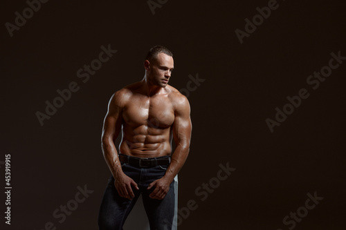 Male muscular athlete sitting on cube in studio