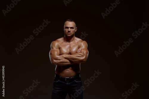 Male muscular athlete shows his power in studio