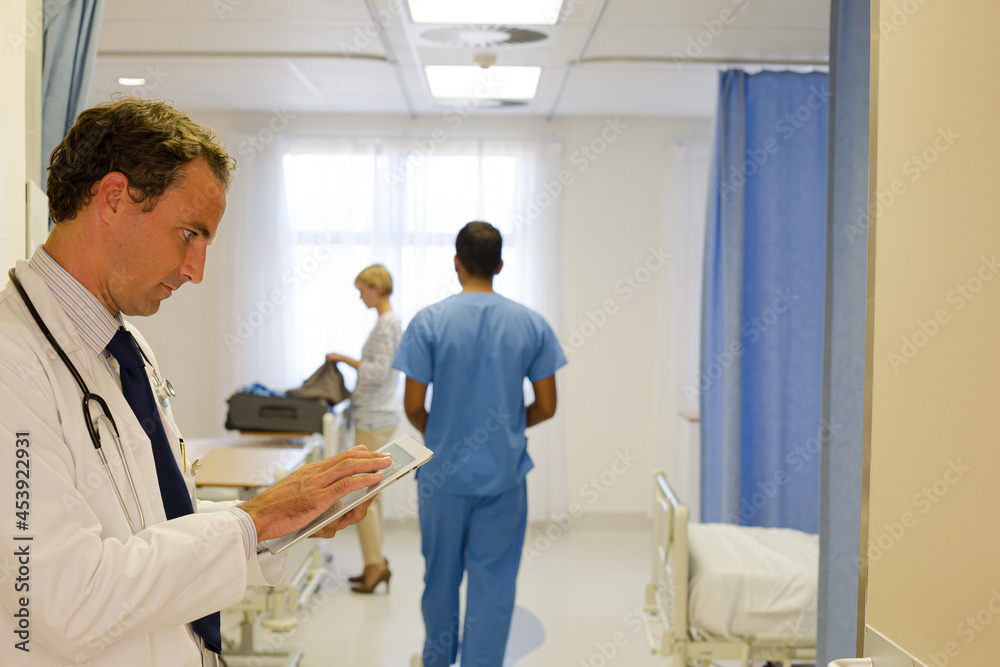 Obraz premium Doctor reading clipboard in hospital room