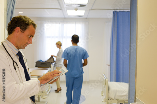 Doctor reading clipboard in hospital room