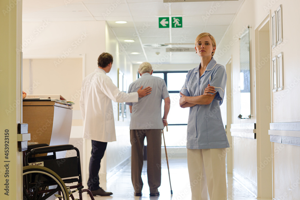 Doctor and nurse standing with patient in hospital hallway Doctor and nurse standing with patient in hospital hallway