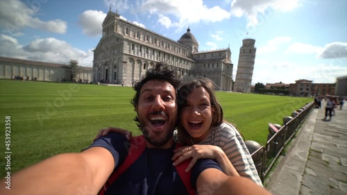 Travel tourists friends taking photo selfi with smartphone in Pisa, Tuscany. happy couple in love traveling in Europe having fun taking self-portrait picture in Pisa by Leaning Tower of Pisa, Italy.