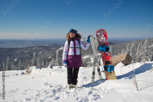 A woman in ski equipment is standing on the top of a mountain. A girl at a ski resort