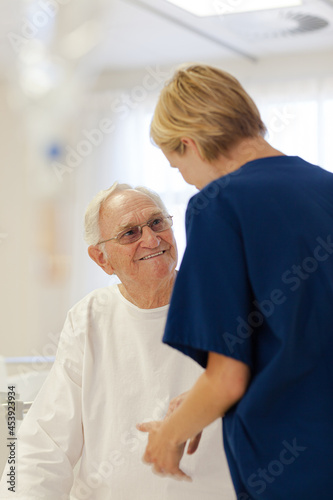 Nurse reading older patient's medical bracelet in hospital