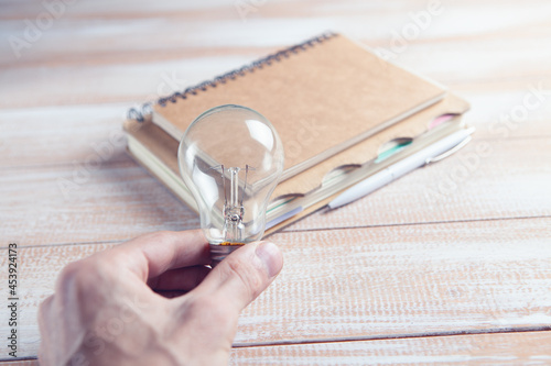 holding a light bulb by a notebook