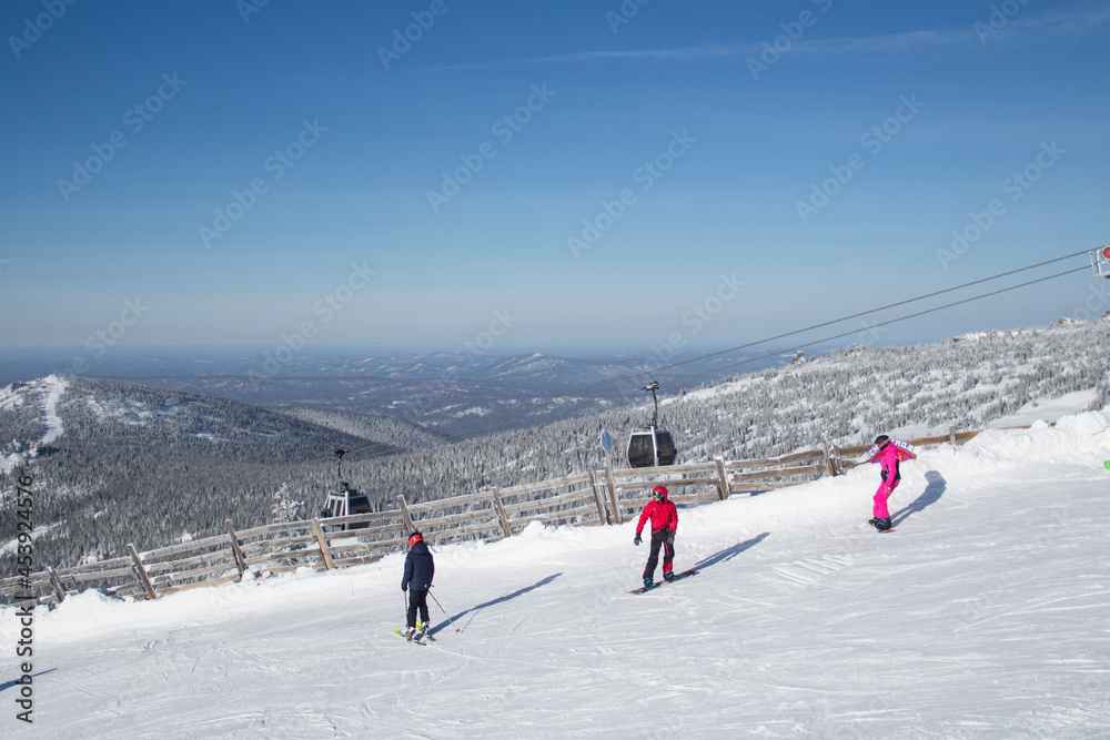 The ski slopes of the resort. Skiers and snowboarders on the slope of the ski resort