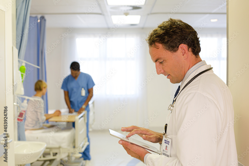 Fototapeta premium Doctor reading clipboard in hospital room