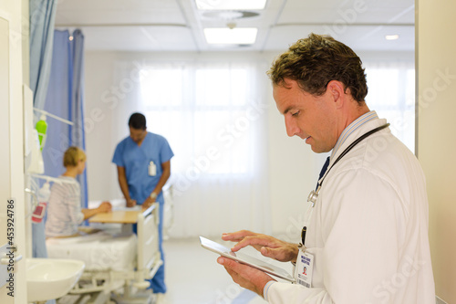 Doctor reading clipboard in hospital room
