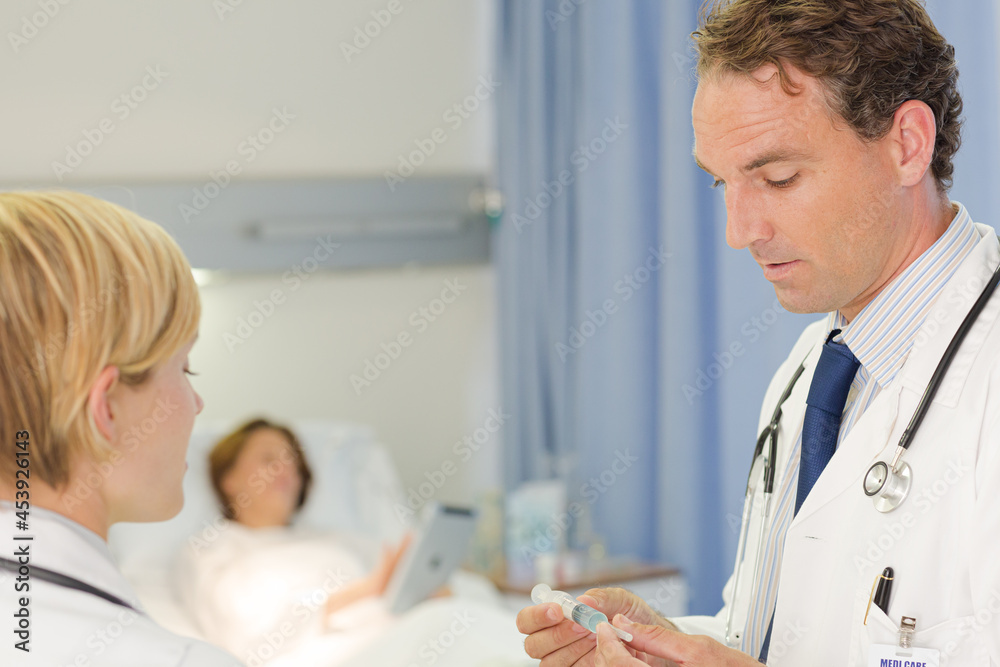 Fototapeta premium Doctor checking syringe in hospital room