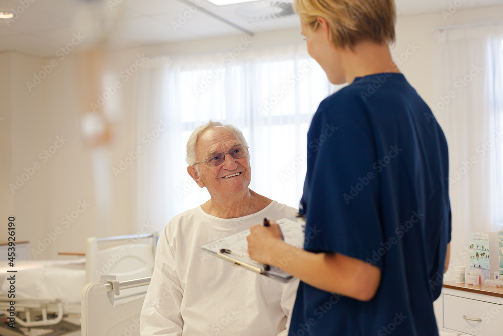 Fototapeta premium Nurse and older patient talking in hospital room