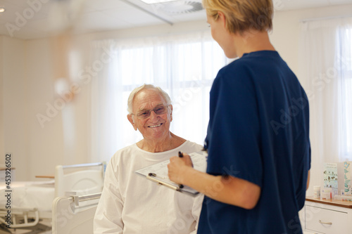 Nurse and older patient talking in hospital room